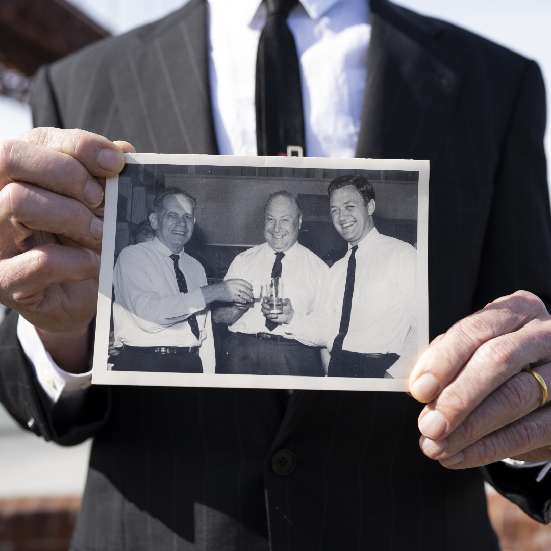 A Global Merchandising leader holding a photo of the three founders